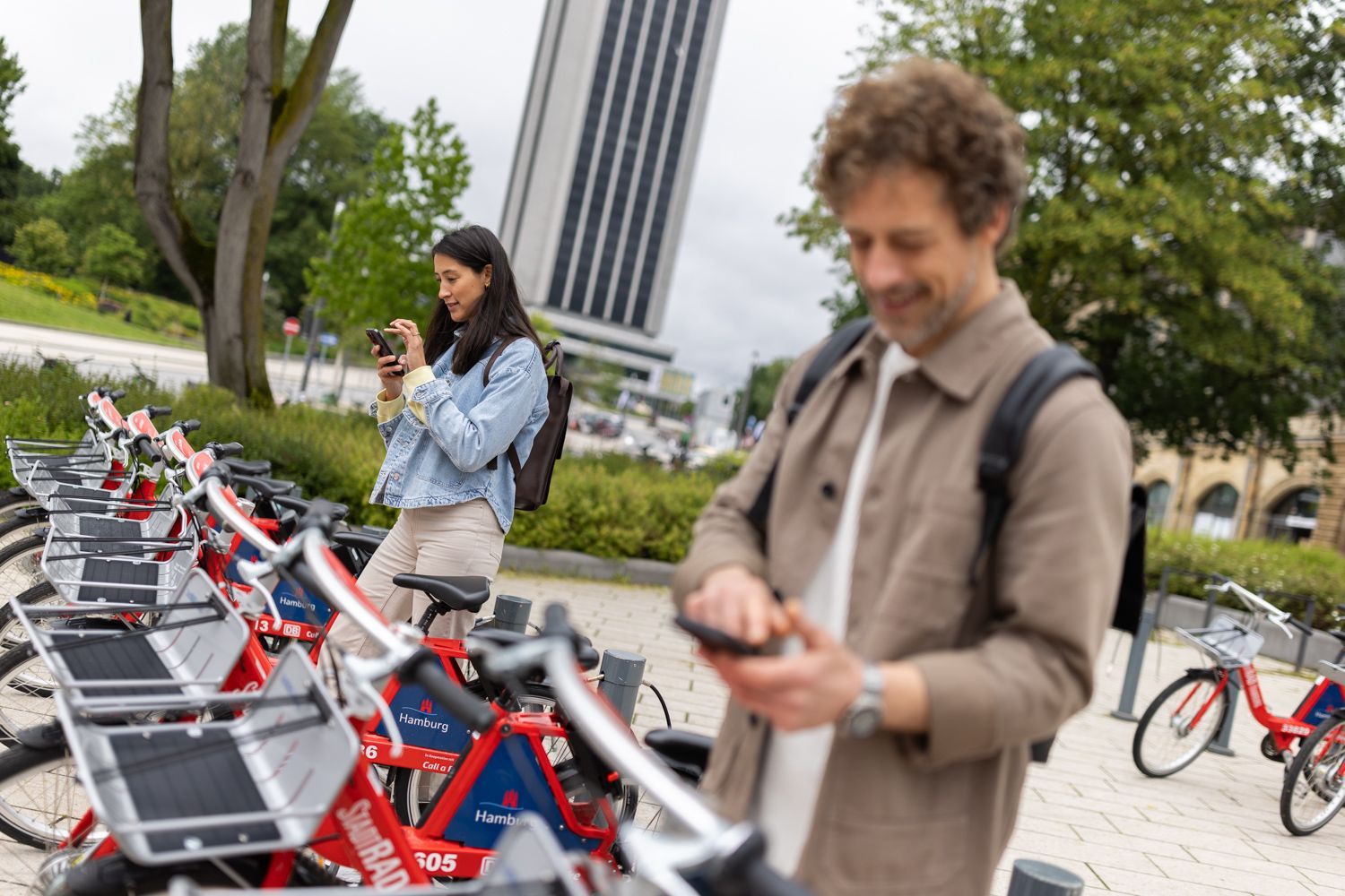 Two people standing at a StadtRAD station and download the StadtRAD app